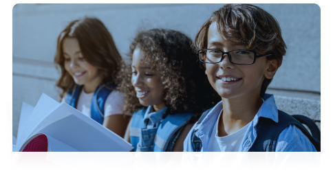 Three elementary students with books, representing the Acadience Reading K-6 audience