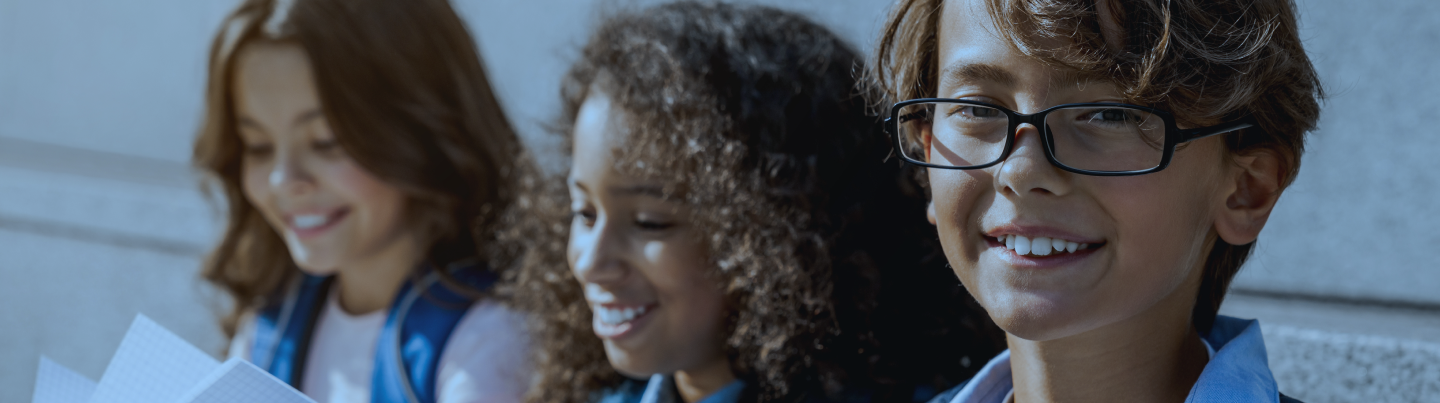Three elementary students with books, representing the Acadience Reading K-6 audience