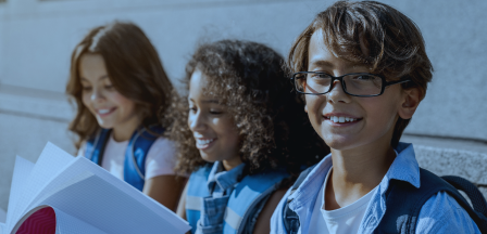 Three elementary students with books, representing the Acadience Reading K-6 audience